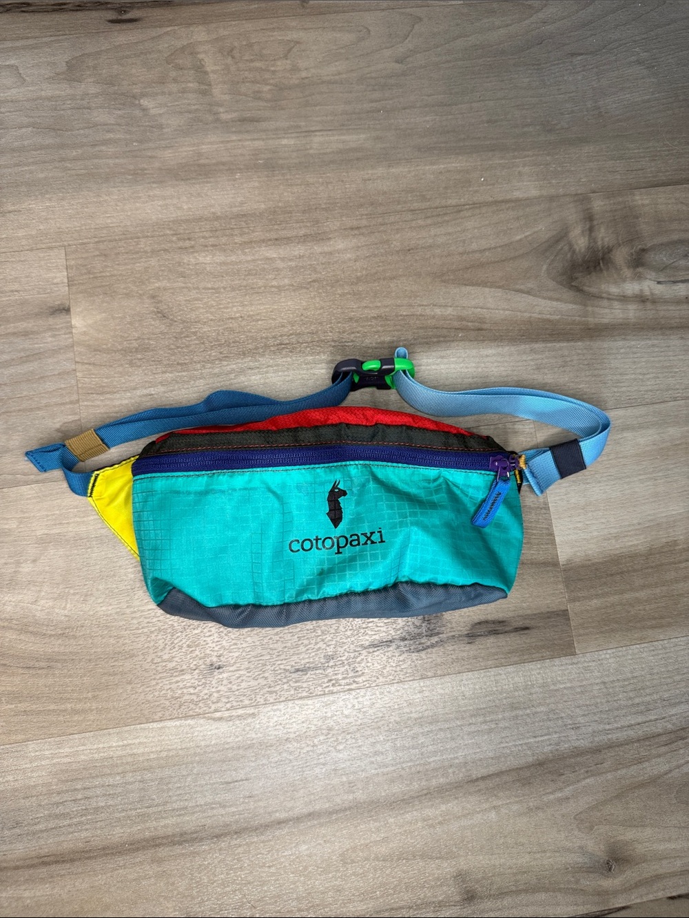 cotopaxi teal waist pack with yellow, red, purple and blue accents